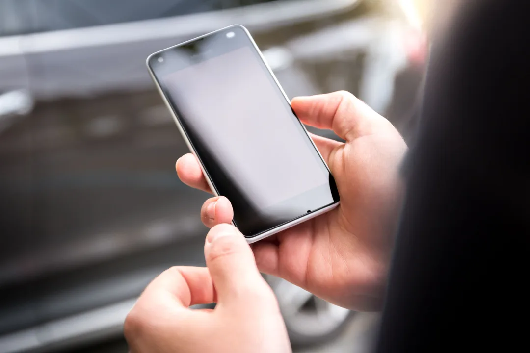 Traveler checking a phone while waiting at an airport gate before departure