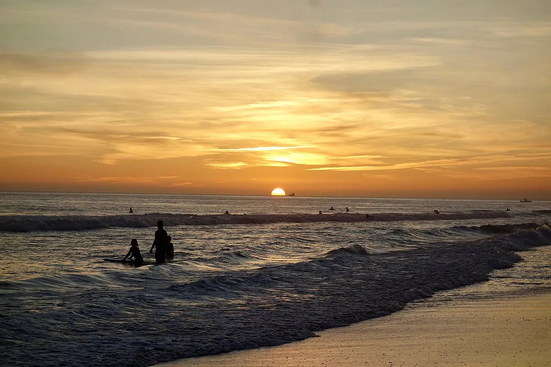 Surfers and families on the wide sand of Carcavelos beach near Lisbon
