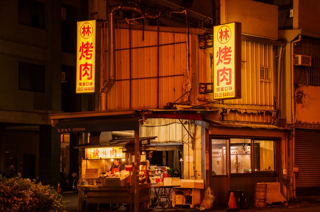Night street food stall with bright signs and prepared dishes