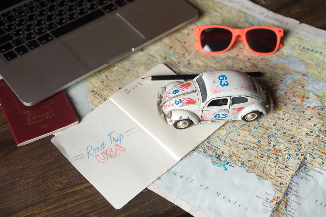 Passports, a route map and a laptop laid out on a table while a couple plans their trip